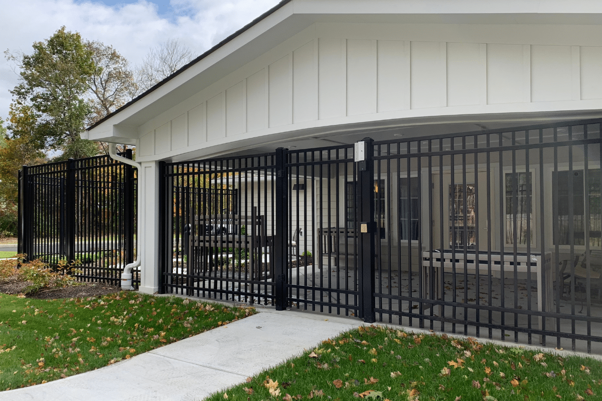 A chain-link fence with a GMH sign stands in front of tall metal warehouse shelves filled with cardboard boxes. Taken in Enfield, CT.