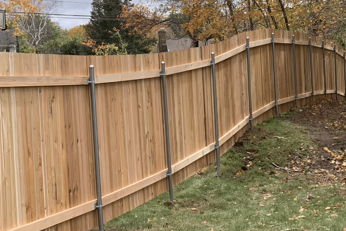 Cedar board privacy fence on sloped yard with reinforced steel posts installed along a sloped backyard property line in Avon, CT.